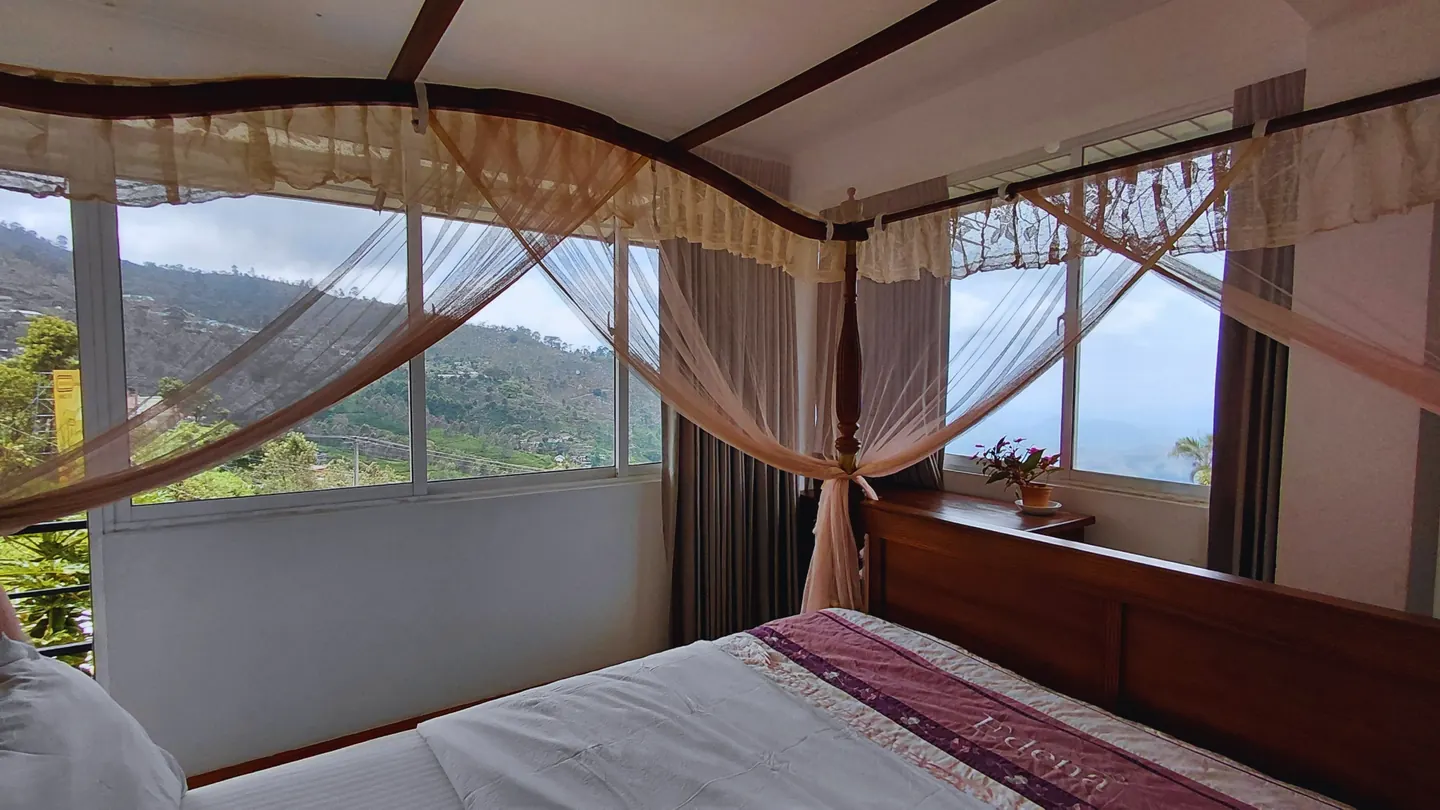 A guest room at The Mist with a bed beside wide windows.
